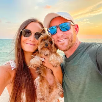 couple with dog at sunset 